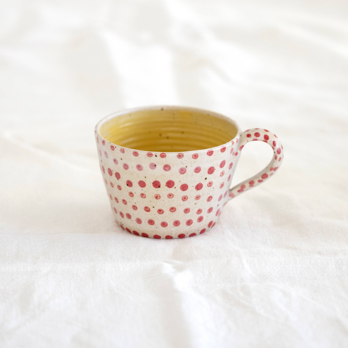 Coffee mug with red polka dots yellow glaze